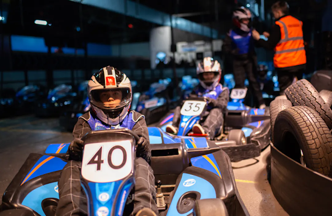 Young racer driving a junior kart, in pit lane during a kids’ karting session