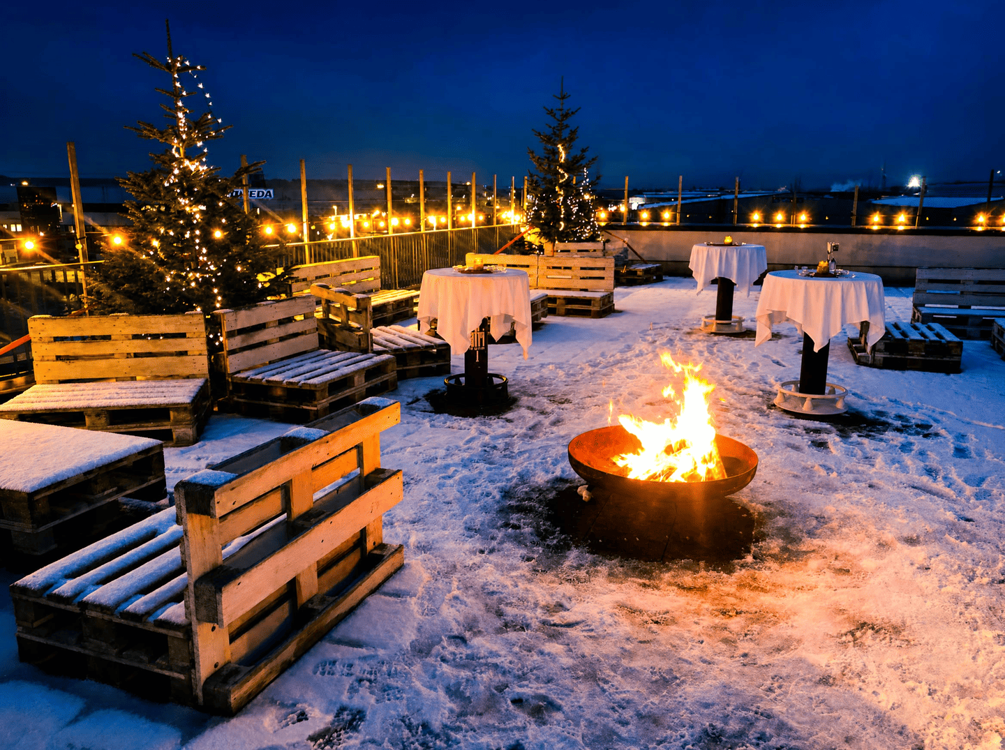 Weihnachtlich geschmückte Dachterrasse mit Schnee und Lagerfeuer