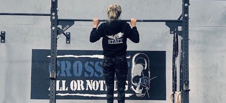 A CrossFit box member doing pull-ups in a CrossFit gym