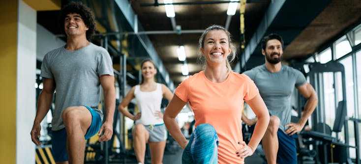 A step class in a gym with gym equipment in the background
