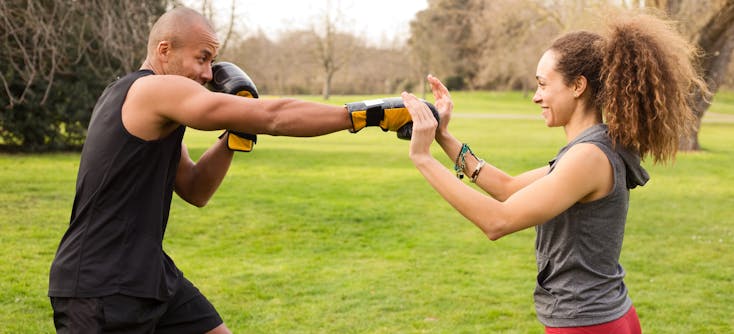 A trainer taking a boxercise session in a park with a personal training client.