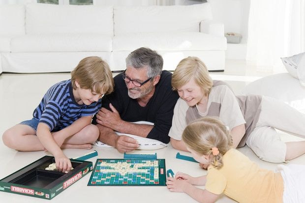 Adult playing a board game with three kids.