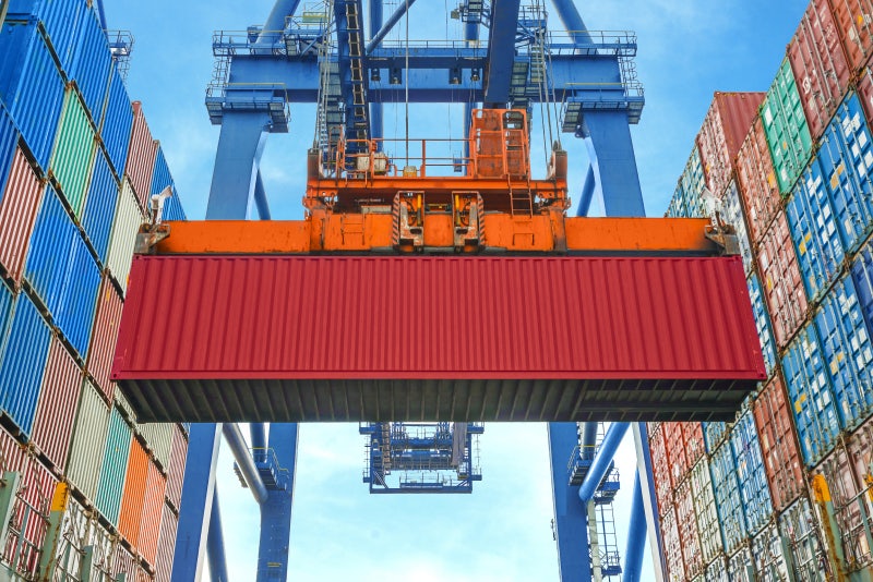 A spreader lifting a red container.