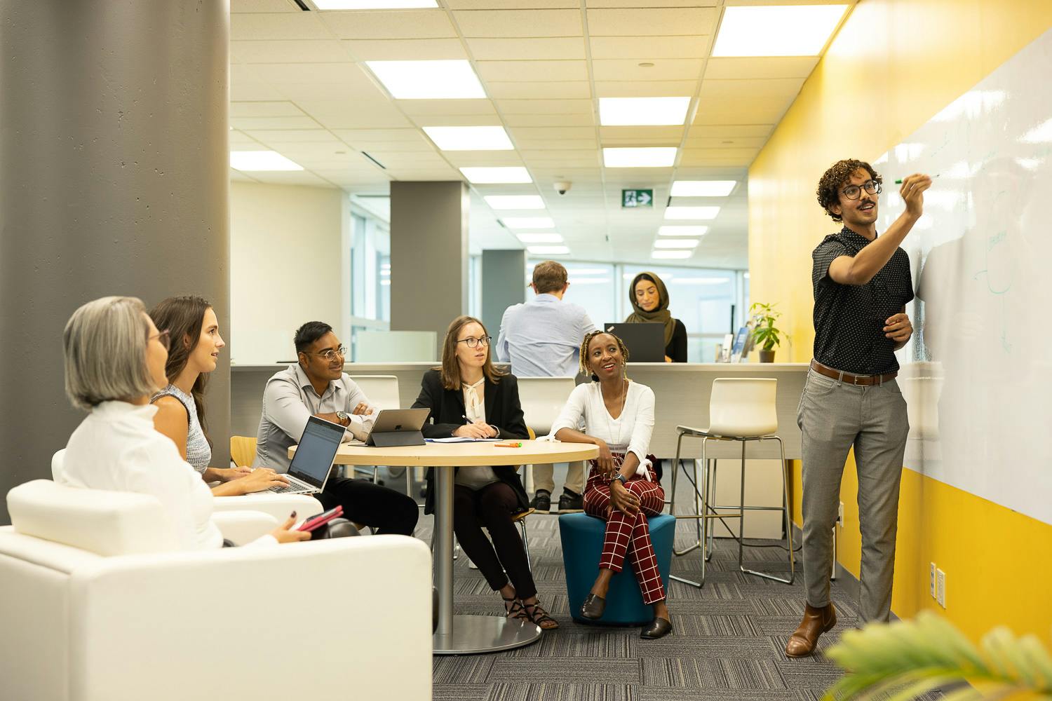 Seated group watches team leader write on a white board