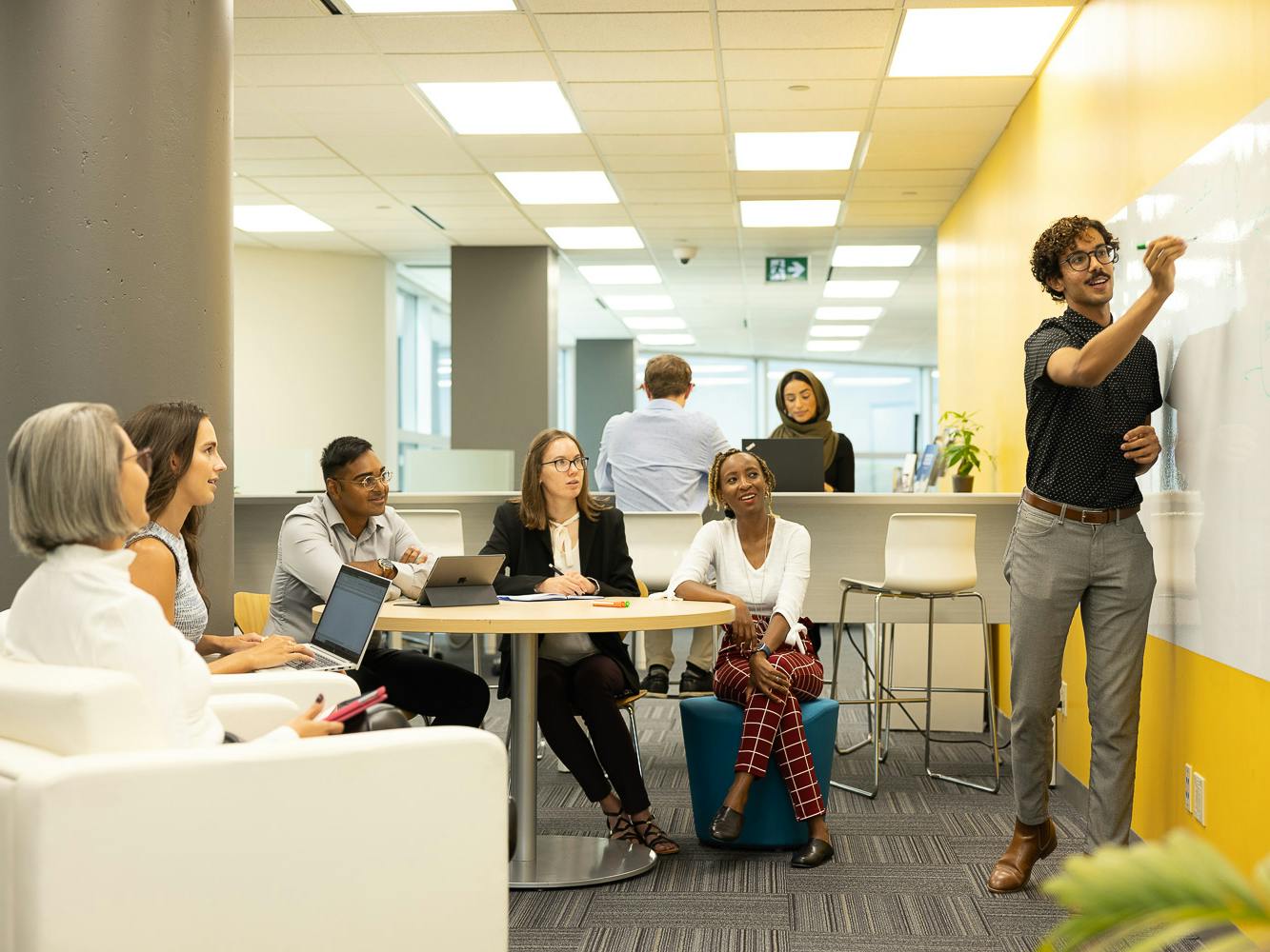 Seated group watches team leader write on a white board