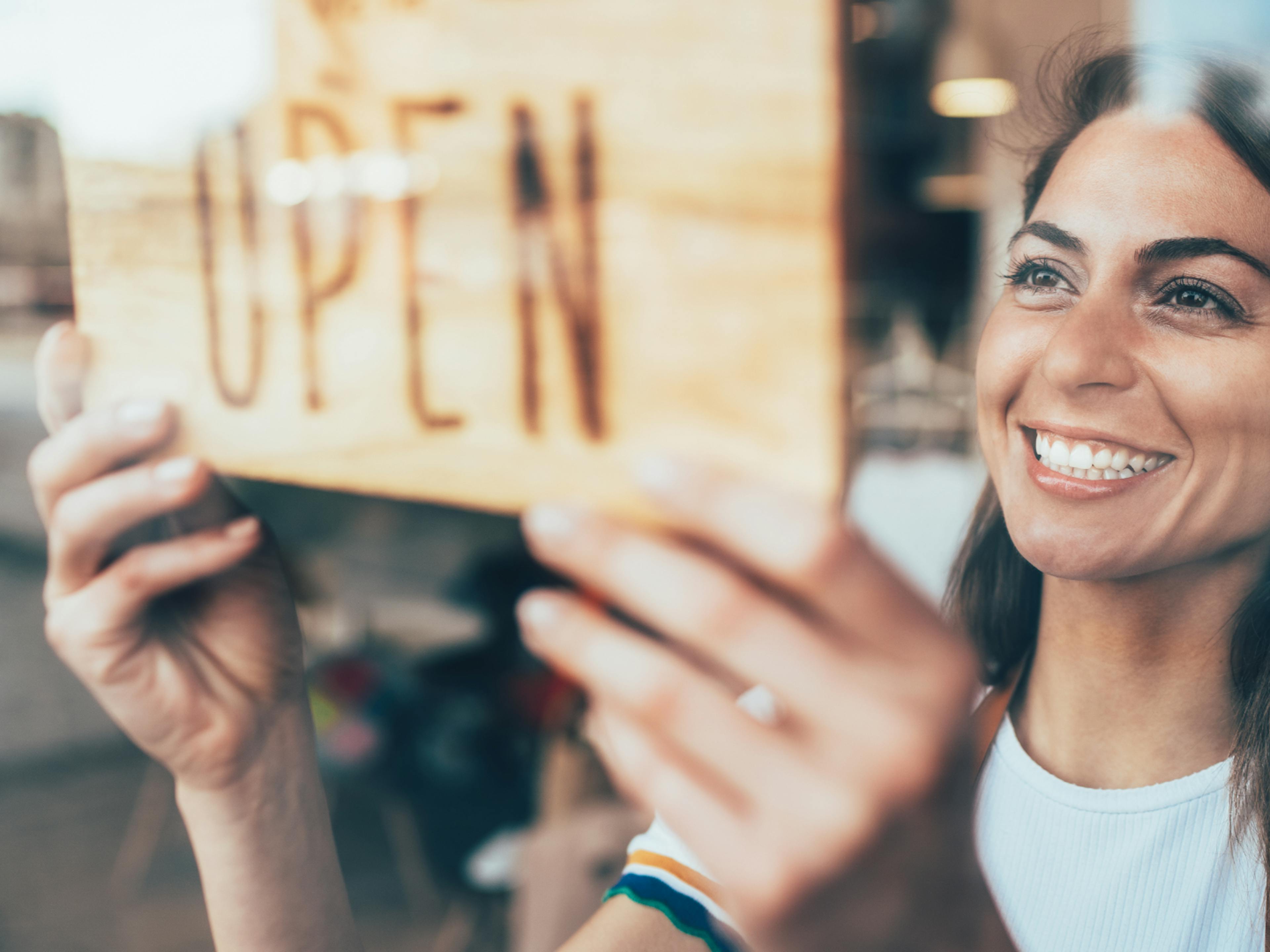 A lady holding open sign for a business