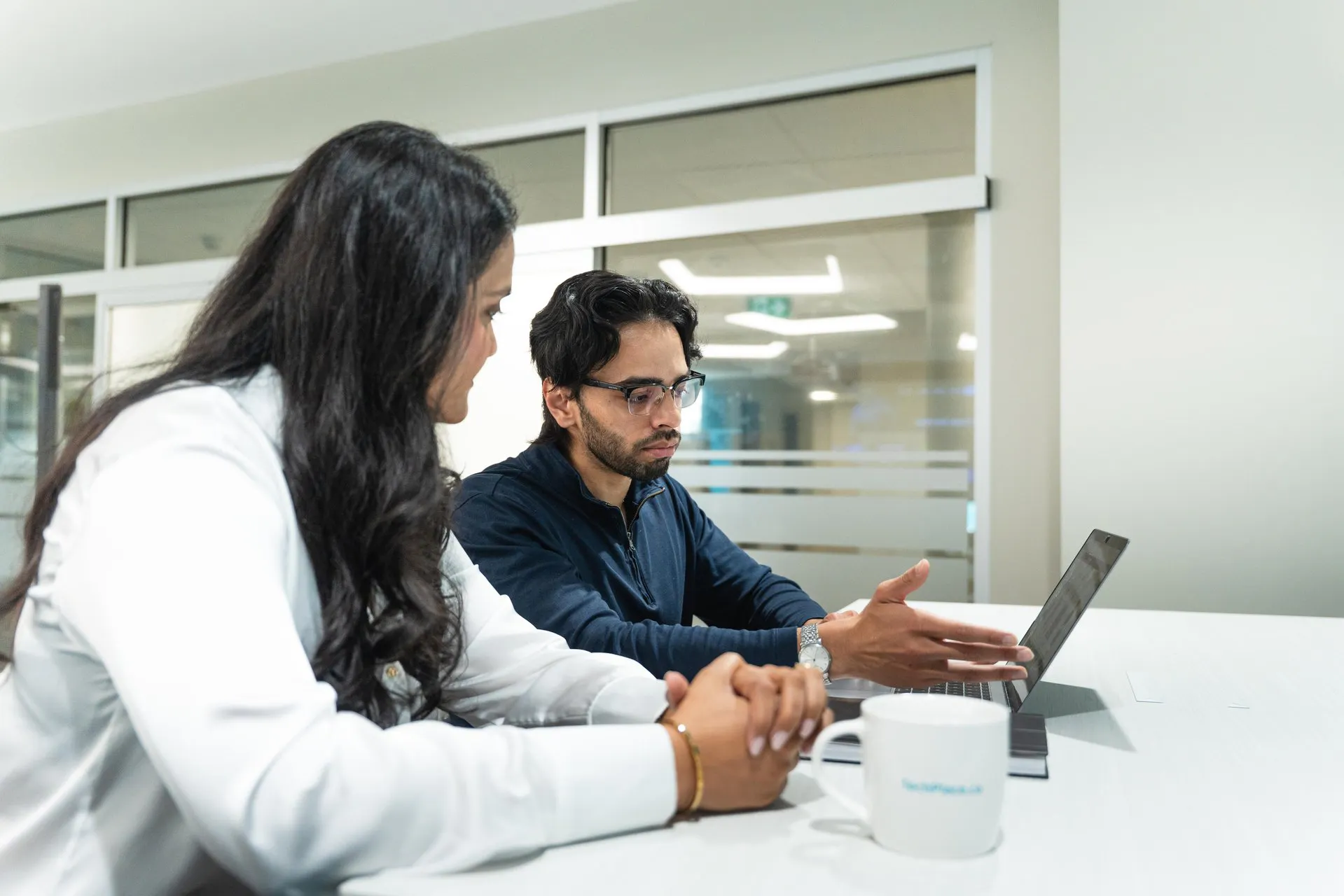 Two people sitting at desk looking at computer screen