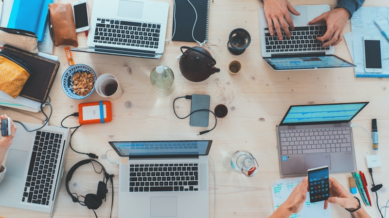 Office work table with staff on their laptops.