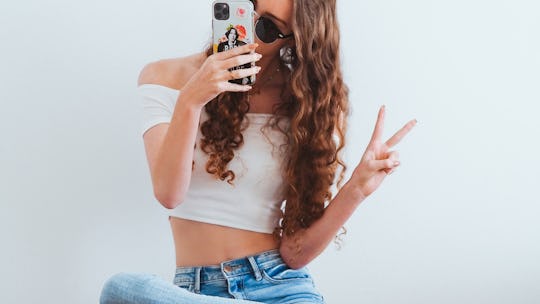A social media content creator talking a selfie with the peace sign