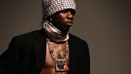 Rema poses with a chain around his neck