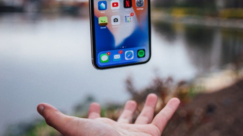 An iPhone smartphone floating above a hand