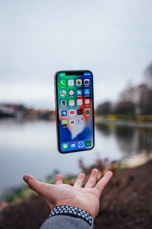 An iPhone smartphone floating above a hand