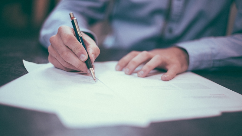 Individual writing on plain paper.