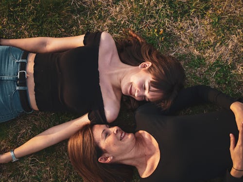 Mother and daughter lying on green grass staring into each other's eyes