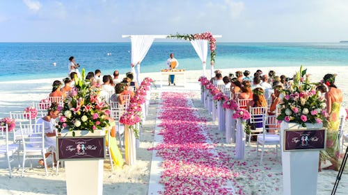Image showing wedding guests and an officiating priest at a destination wedding held in front of a beach