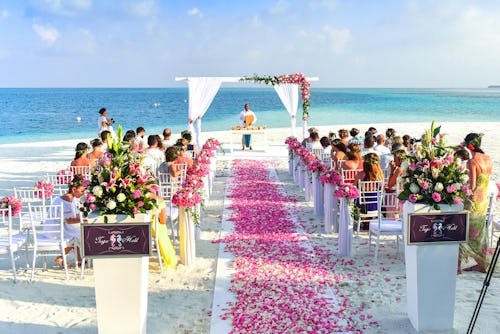 Image showing wedding guests and an officiating priest at a destination wedding held in front of a beach