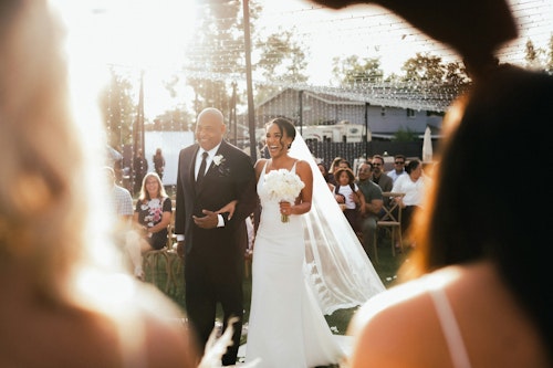 A bride walking down the aisle on her wedding day with her father holding her hands