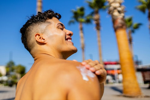 Image of a man applying SPF sunscreen during the day to prevent sunburn