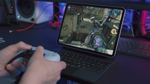A gamer playing a video game on a laptop with a game pad