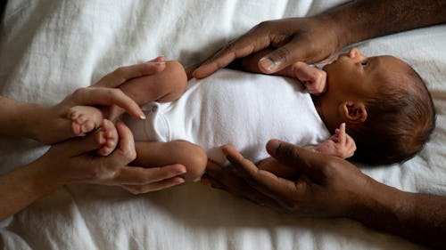 Interracial couple holding on a baby lying on a bed