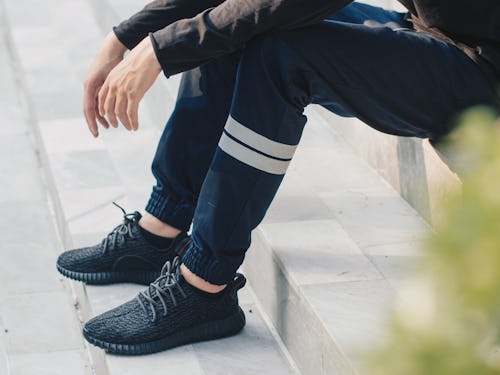 A man wearing black trainers sitting on steps