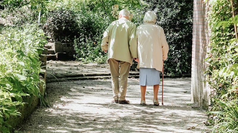 An elderly couple walking in a park.
