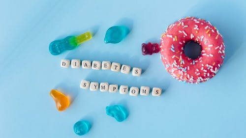 Image showing doughnut and gummies placed on a table with the inscription, "diabetes symptoms"