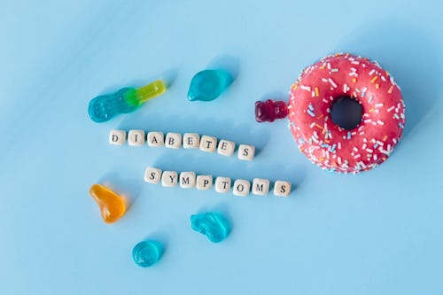 Image showing doughnut and gummies placed on a table with the inscription, "diabetes symptoms"