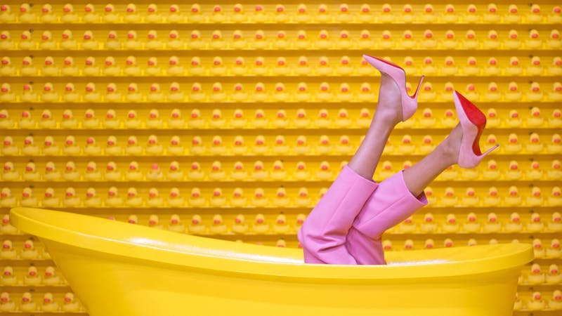 A woman on high heels lying inside a bath tube