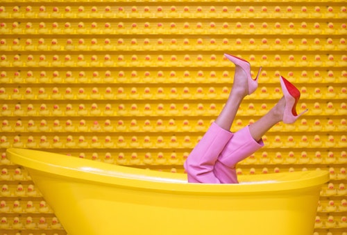A woman on high heels lying inside a bath tube