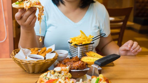A woman eating high-calorie meal that contains unhealthy fat