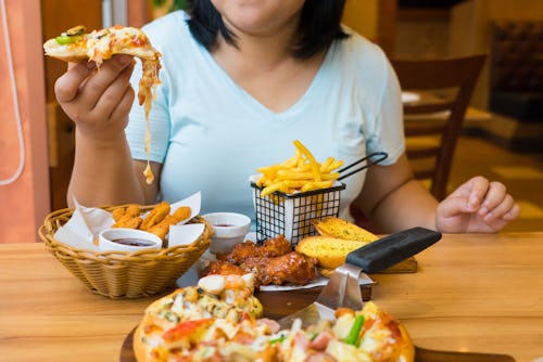 A woman eating high-calorie meal that contains unhealthy fat