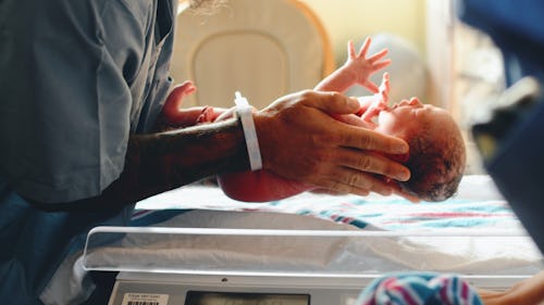 Image of a nurse carrying a crying newborn baby