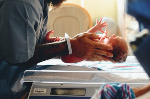 Image of a nurse carrying a crying newborn baby