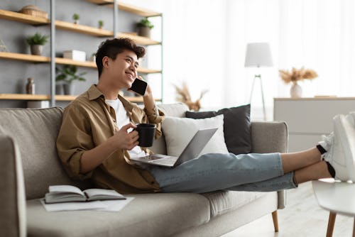 A man working with laptop placed on his laps drinking coffee