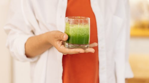 Image of a person carrying a glass of a plant juice extract