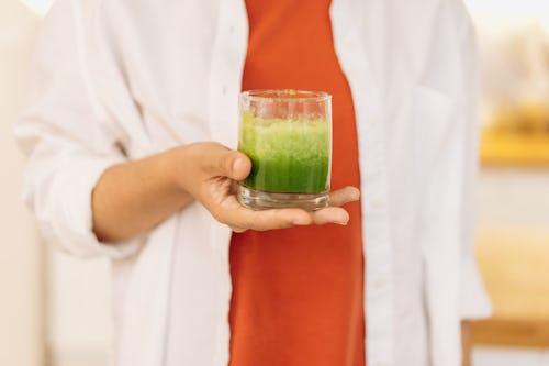 Image of a person carrying a glass of a plant juice extract