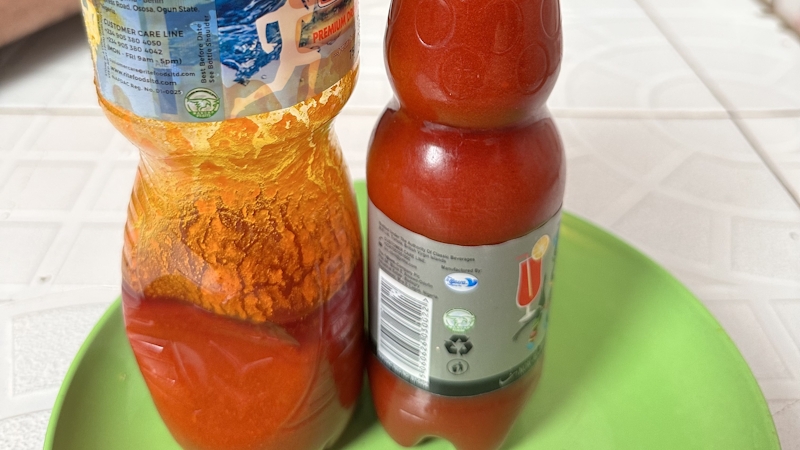 Two bottles of red oil placed on a green plate