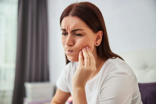 Image of a lady with a painful expression on her face with hands placed on her jaws