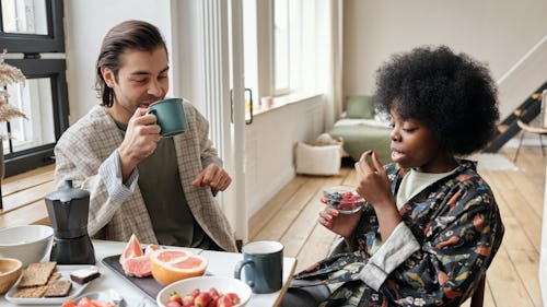 A man and a woman eating food and drinking coffee