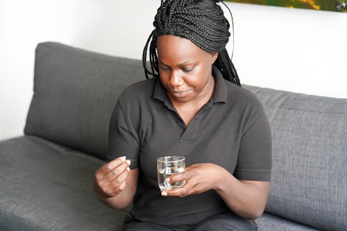 Black woman taking medication to treat hormonal imbalance