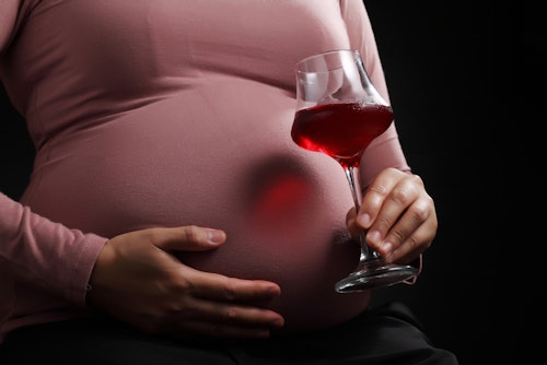 A pregnant woman carrying a glass of zobo drink