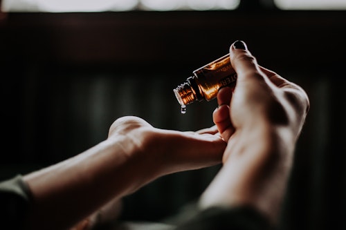 A woman pouring out oil from a bottle to apply on her skin