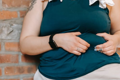 A woman gripping the muscles of her abdomen with her two hands