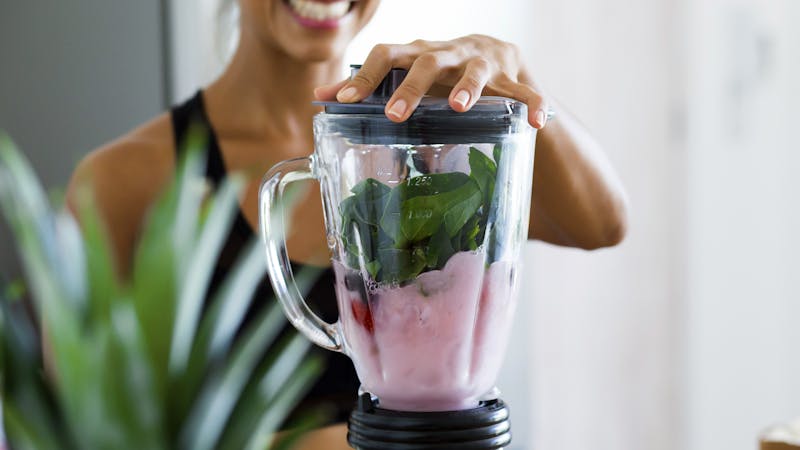 A woman blending vegetable detox smoothie for belly fat lose