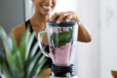 A woman blending vegetable detox smoothie for belly fat lose