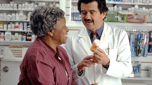 Pharmacist prescribing medication to an older woman in a pharmaceutical shop