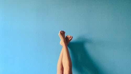 Image of the leg of a person with a high arched feet resting on the wall