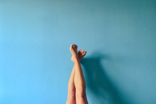 Image of the leg of a person with a high arched feet resting on the wall