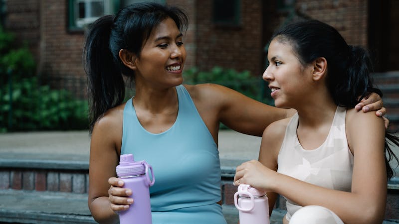 Two women drinking collagen water after working out
